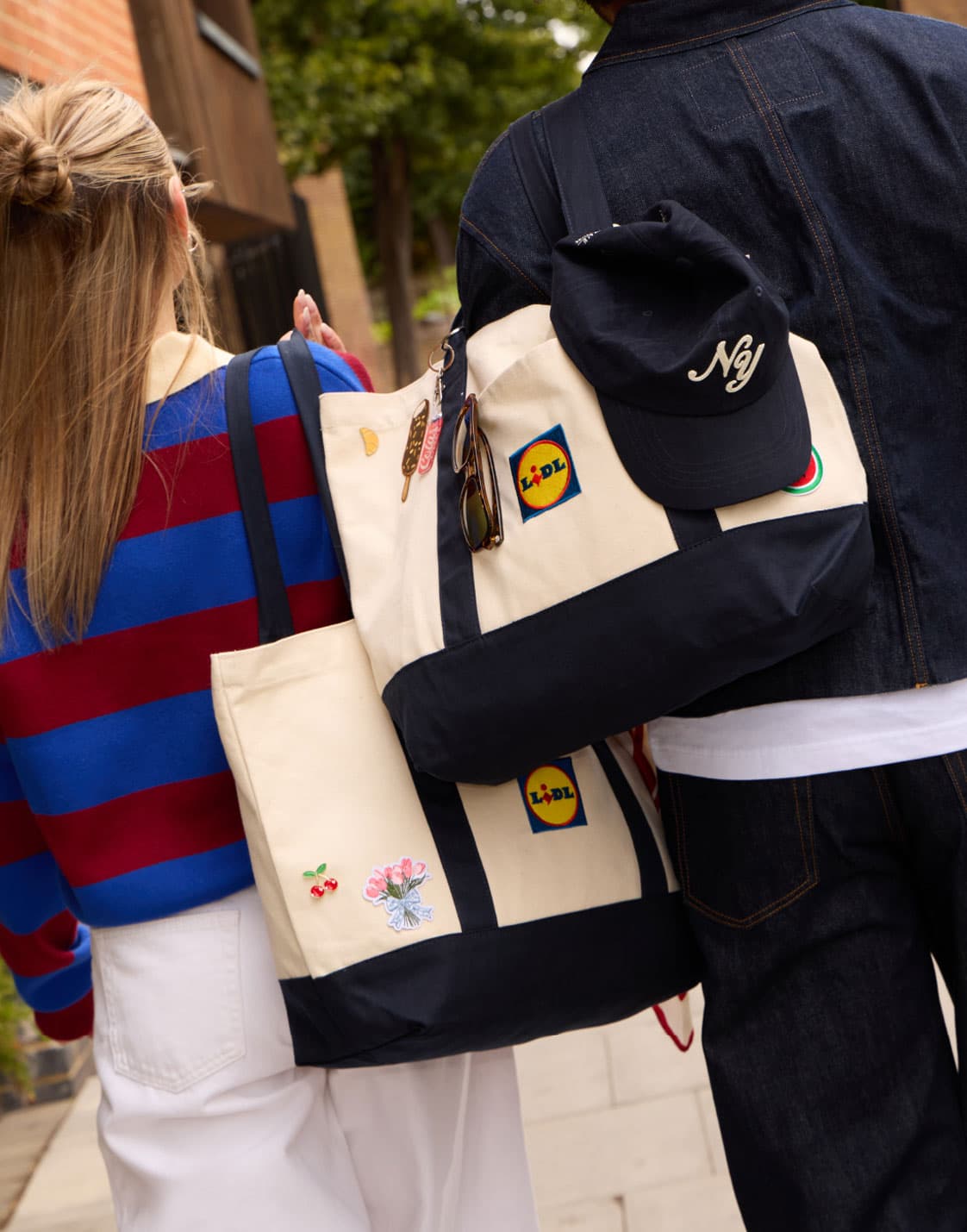 Two shoppers carrying Lidl totes decorated with accessories